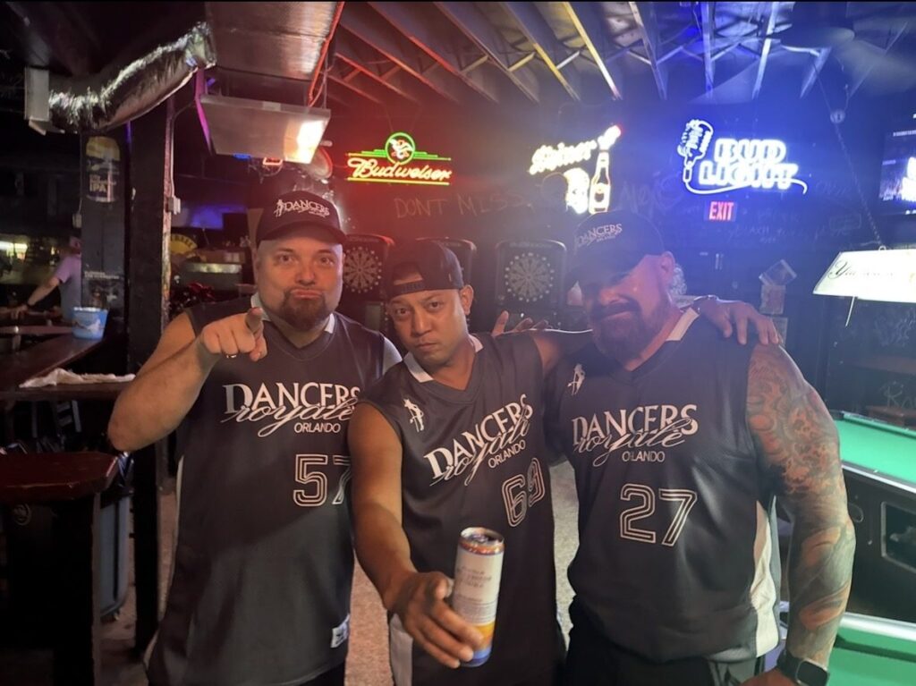 The Dancers Royale Orlando crew in team jerseys by the pool tables and bar