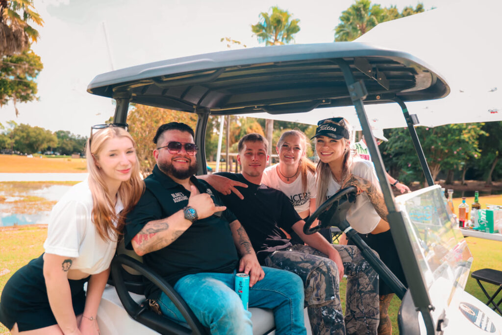 A foursome with Dancers Royale entertainers in a golf cart at the charity tournament